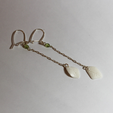 boucles d'oreilles en porcelaine blanche en forme de feuille, en haut une petite perle à facettes verte, sur longue chainette et crochet en argent